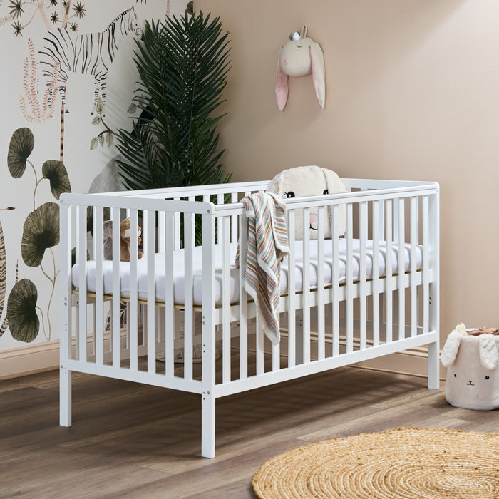 white cot bed, with rails on all 4 sides, teething rails on the longest sides, base on the new born setting for easy access for parents to lean in.
