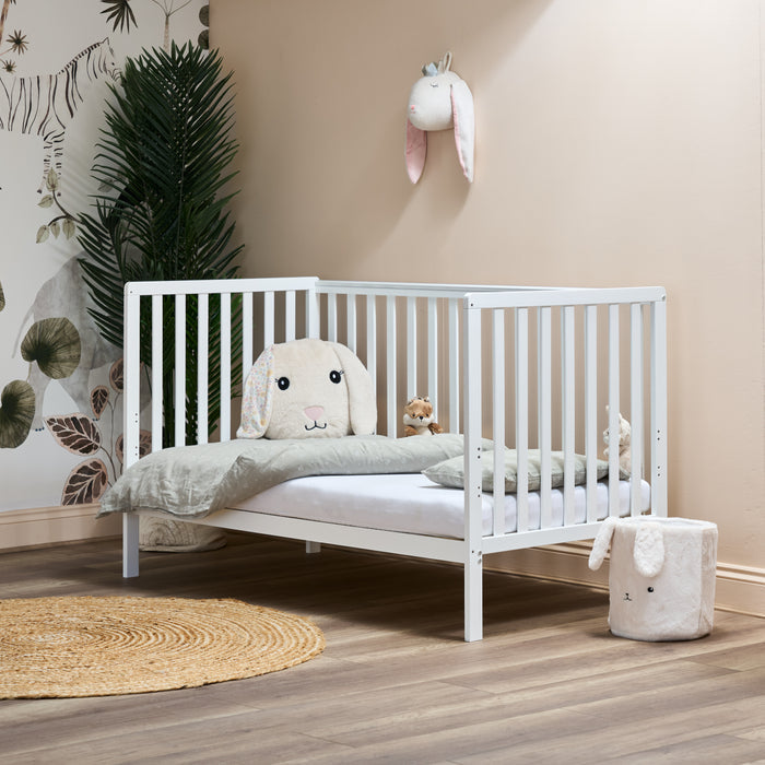 White cot bed, in day bed mode with rails on all 3 sides, low mattress setting for toddlers easy access.