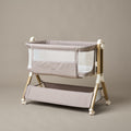 Bedside crib with taupe woven fabric, mesh sides, zipped up parent window, wood effect frame with ivory plastics & wheels. Storage basket underneath.