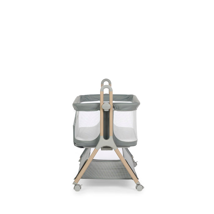 Baby bedside crib with sage fabric, mesh windows on all 4 sides, wood effect frame with grey plastics & casters. Crib height at its lowest setting. Storage basket under crib.