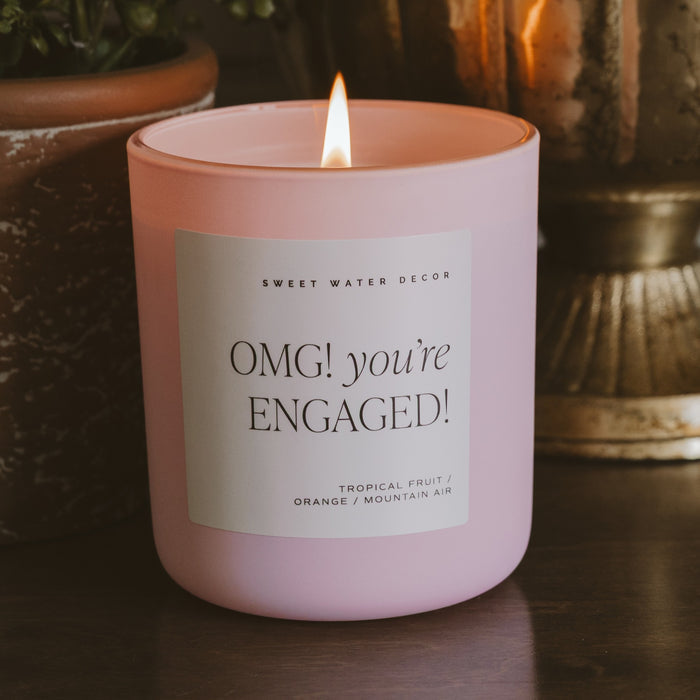 Pink engagement soy candle by Sweet Water Decor with tropical fruit scent, burning with flame