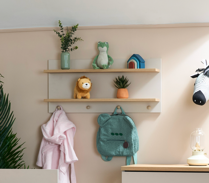 Children's room with shelves displaying toys and a backpack, wall hooks with a towel and backpack, and a lamp.