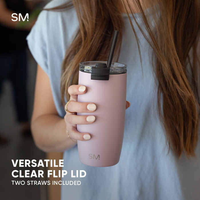 Woman holding pale pink Simple Modern insulated tumbler with black flip lid and straw. Text reads "Versatile Clear Flip Lid" and "Two Straws Included." Soft lifestyle product photography.